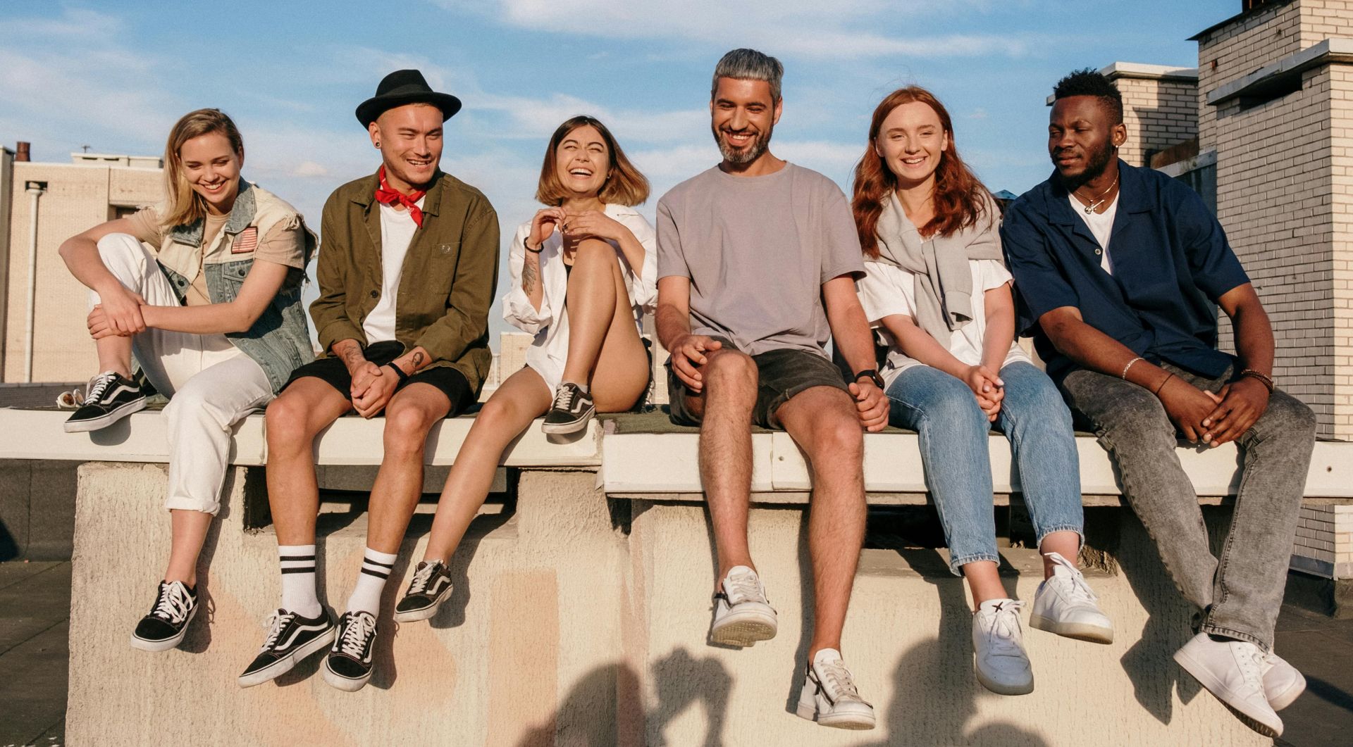 Diverse group of friends laughing and relaxing on a sunny rooftop.